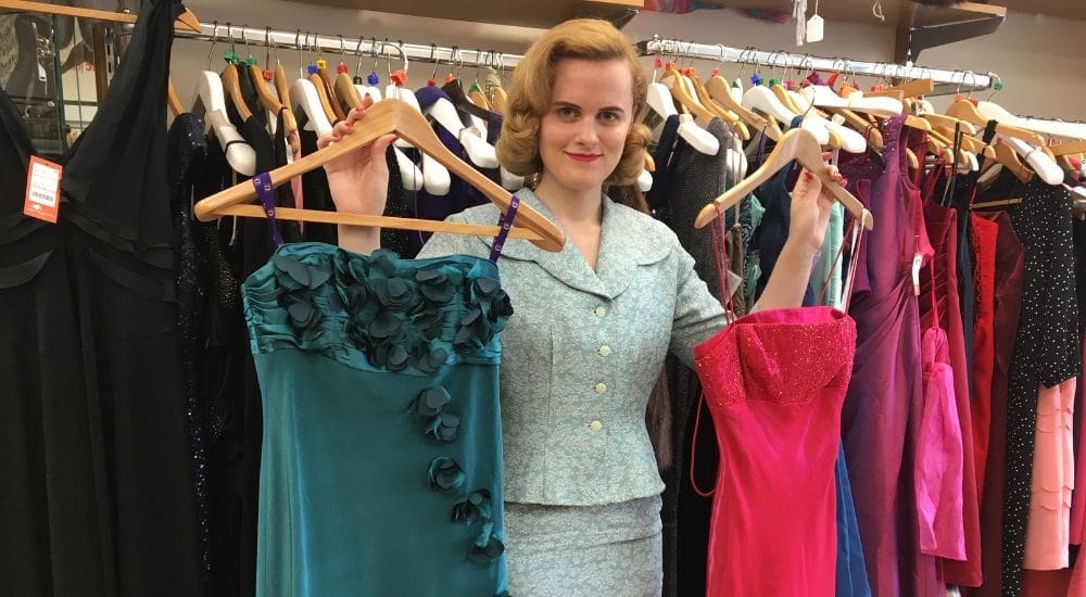 Woman shop volunteer with blue and pink dresses