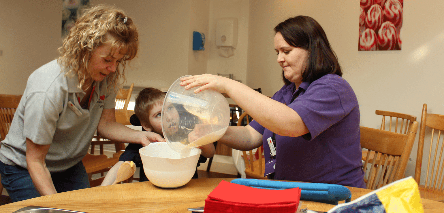 Volunteer Julie with HDH nurse and child baking_1500x700