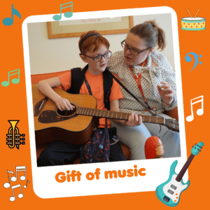 'Gift of a music' graphic showing a boy playing on the guitar, part of Charity Gift Cards