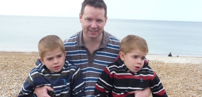 A man at the beach with his twin sons