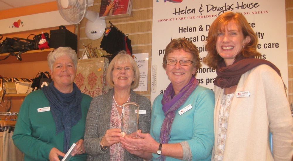 4 women Helen & Douglas House staff smiling with glass trophy