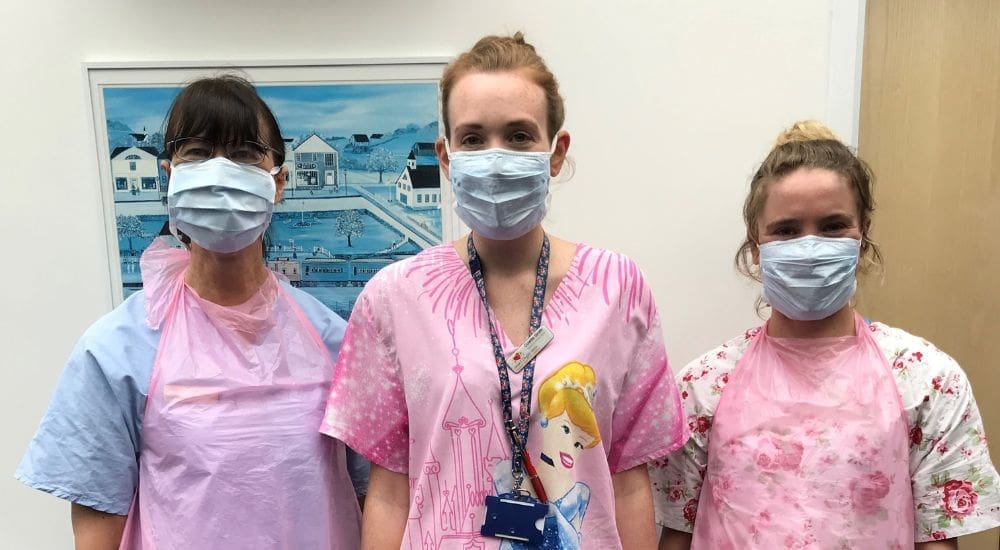 3 hospice nurses with masks on and colourful uniforms