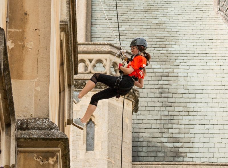 A woman abseiling down the side of a building.